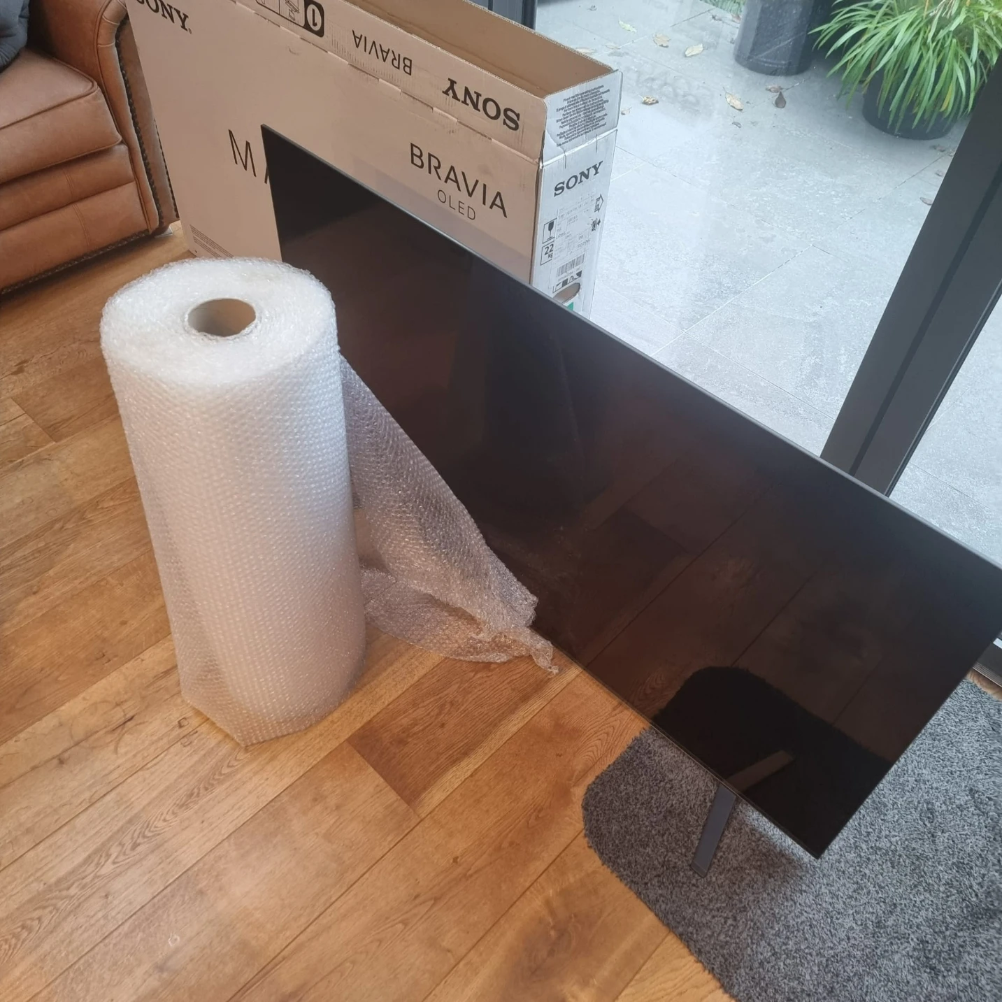 FLat SCreen TV standing next to a bubble wrap, tape and boxes